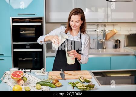 belle jeune femme qui verse du lait d'un pot à l'autre. chef qui verse du milk-shake dans le pot. photo en gros plan Banque D'Images