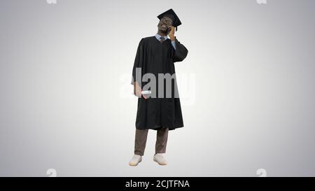 Un homme afro-américain souriant en robe de remise des diplômes parlant Banque D'Images