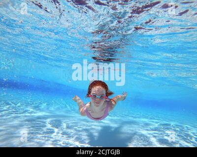 Jeune fille à tête rouge natation sous-marin avec des lunettes dans un Piscine