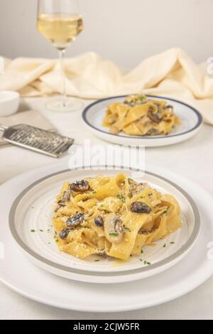 Pâtes italiennes maison à la fettuccine aux champignons et au parmesan (Fettuccine al Fonghi Porcini). Cuisine italienne traditionnelle. Servi avec de la vigne. Banque D'Images