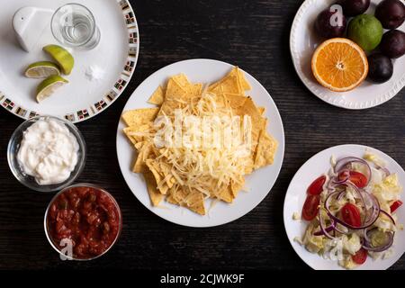 Déjeuner mexicain composé de nachos ou de tortillas et de fromage, avec salsa et crème sure, salade et fruits, et un verre de tequila au citron vert Banque D'Images