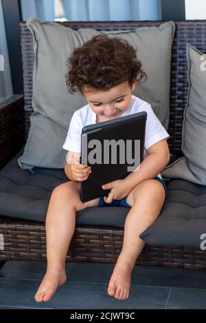 Un adorable enfant maurique utilisant une tablette numérique. Gros plan d'un garçon d'âge préscolaire à l'aide d'une tablette électronique. École, enseignement à distance, appel vidéo à la maison. Banque D'Images