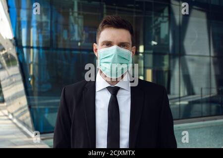 Homme d'affaires portant un masque médical dans le centre d'affaires. Homme d'affaires en costume noir Banque D'Images