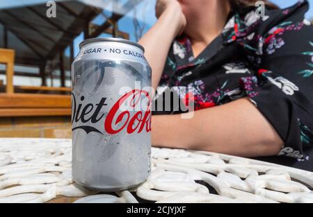 Femme assise à une table à l'extérieur lors d'une journée chaude en été avec une cane de Coca-Cola Light, au Royaume-Uni. Banque D'Images