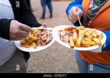 Couplez avec deux assiettes en papier contenant des frites et du currywurst Banque D'Images