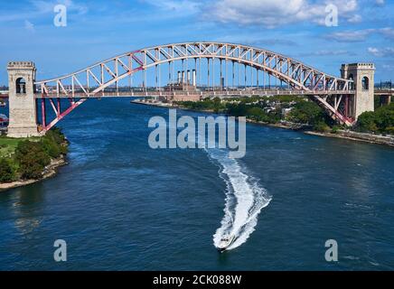 Le bateau de moteur quitte un sillage en passant sous le pont du chemin de fer Hell Gate, en traversant la rivière East, New York, NY. Banque D'Images