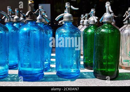 Une collection de bouteilles de siphon en verre de couleur vintage sur une table dans un magasin d'antiquités de New York. Banque D'Images