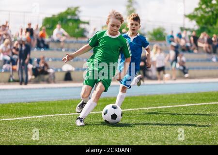 Jeunes garçons jouant au football. Les enfants s'amusent dans le sport. Les enfants heureux participent à un match de football. Joueurs de football de course. La compétition entre les joueurs s'exécute Banque D'Images