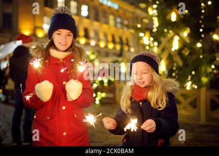 Deux adorables sœurs tenant des spameux près d'un arbre de Noël sur la foire traditionnelle de Noël à Riga, Lettonie. Les enfants fêtent le nouvel an. Tim. Hiver Banque D'Images