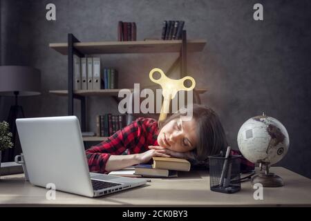 Une jeune fille étudiante fatiguée dort au-dessus de ses livres à la maison et il a besoin d'une charge Banque D'Images