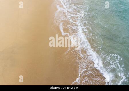 Vue sur la mer, depuis un quai, des vagues de l'océan se lavant sur une plage de sable. Banque D'Images