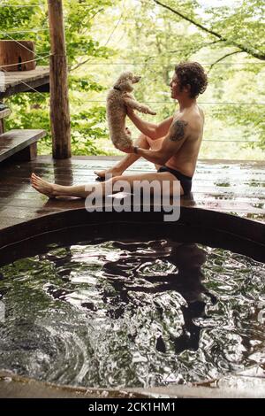 un jeune homme sous le pantalon va avoir un bain avec un chien de pediggree. pleine vue latérale photo. Banque D'Images