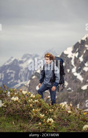 le touriste actif se balade parmi les buissons de la montagne. les montagnes enneigées sont étonnantes sur le fond de la photo.photo pleine longueur. Banque D'Images