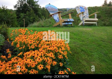 Fauteuil Adirondack géant avec peinture pour commémorer le 60 ans anniversaire De Mount Snow Resort avec des fleurs fleuries en premier plan.Mount Snow Station et domaine skiable.Dover.Vermont.USA Banque D'Images