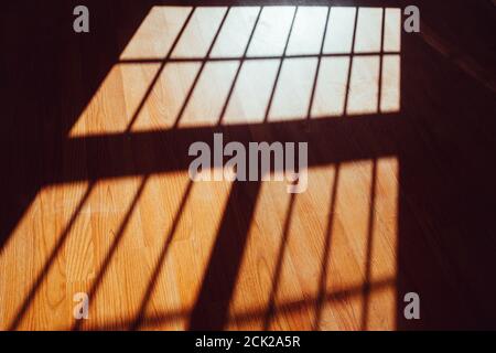 La lumière du soleil pénètre par une fenêtre et projette des ombres carrées contre le parquet. Banque D'Images