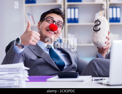 Le clown homme d'affaires dans le bureau avec l'argent A. sac Banque D'Images