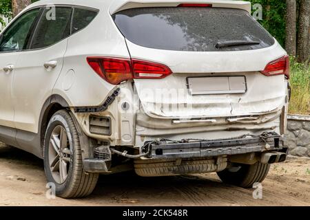 Voiture poussiéreuse endommagée après un accident. Véhicule avec pare-chocs arrière déposé et hayon bosselé. Banque D'Images