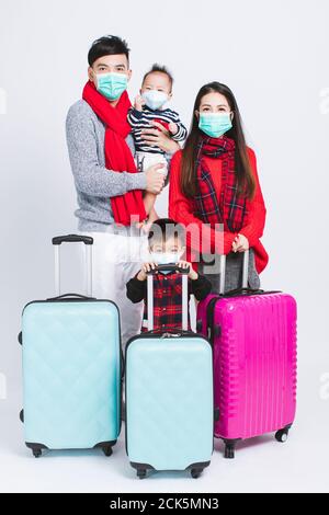 Une famille heureuse portant des vêtements chauds et un masque médical sur fond blanc. Et des concepts de vacances d'hiver Banque D'Images