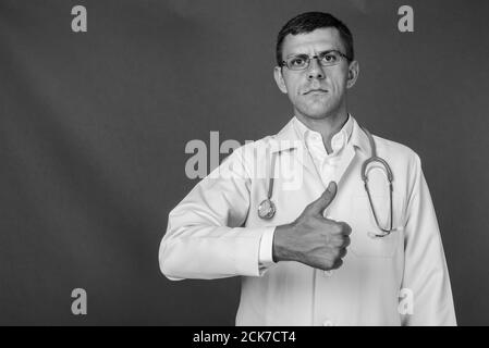 Bel homme médecin aux cheveux courts à l'arrière-plan gris Banque D'Images