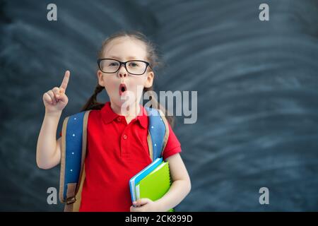 Retour à l'école! Heureux mignon enfant industriel apprend en classe sur fond de tableau noir. Banque D'Images