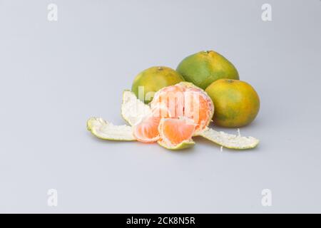 Gros plan d'une mandarine pelée et entière sur un arrière-plan gris Banque D'Images