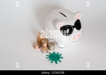 risque d'économies financières dues à un virus pandémique. banque de porc dans un masque sur fond blanc. pièces Banque D'Images