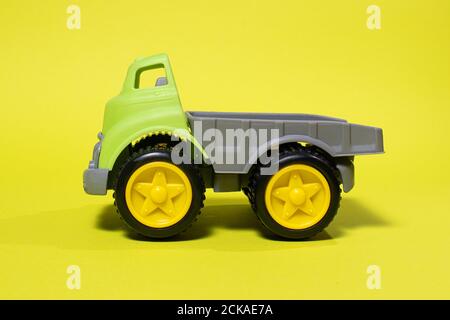 Voiture-jouet sur fond jaune - équipement de construction pour les enfants. Jouets en plastique lumineux pour enfants, camion à benne enfant Banque D'Images