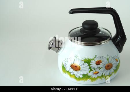 Bouilloire émaillée de blanc avec sifflet, dessin de camomille Banque D'Images