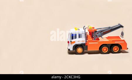 Remorque orange jouet sur fond beige bannière avec espace pour le texte. Voiture pour enfants pour le chargement et le transport de voitures Banque D'Images