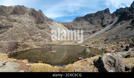 Une marchette solitaire se trouve à côté des eaux de Coire Lagan, sous la crête de Cuillin, dans les montagnes Black Cuillin, à l'île de Skye, en Écosse, au Royaume-Uni Banque D'Images