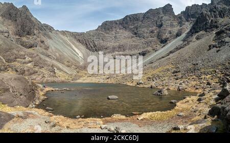 Une marchette solitaire se trouve à côté des eaux de Coire Lagan, sous la crête de Cuillin, dans les montagnes Black Cuillin, à l'île de Skye, en Écosse, au Royaume-Uni Banque D'Images