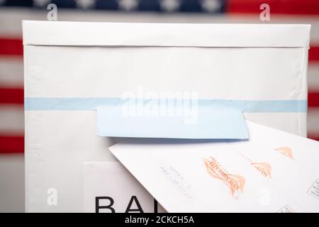 Maski, Inde 14 septembre 2020 : concept de Mail en vote aux élections américaines - gros plan des mains mettant plusieurs mails à l'intérieur de l'urne avec notre drapeau Banque D'Images