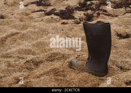 Une seule chaussure wellington noire perdue sur le sable de Saddell Bay, Kintyre, Écosse Banque D'Images