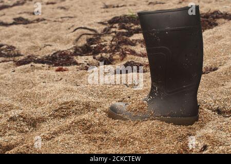 Une seule chaussure wellington noire perdue sur le sable de Saddell Bay, Kintyre, Écosse Banque D'Images