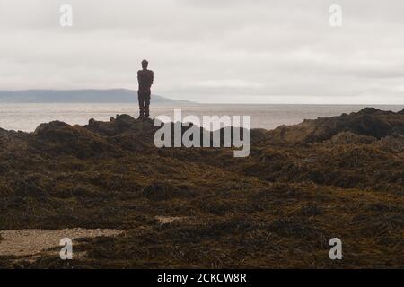 La sculpture d'Anthony Gormley S'ACCROCHE à Saddell Bay, Kintyre, Argyll, en Écosse, sur des rochers qui ont vue sur le détroit de Kilbannan jusqu'à l'île d'Arran Banque D'Images