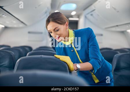 Portrait en gros plan bonne femme attrayante en uniforme bleu d'affaires porter des gants en cuir jaune et un foulard sur la planche d'avion commercial Banque D'Images