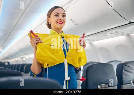 Hôtesse dans la cabine de l'avion passager faisant de la formation d'instructions sur les mesures de sécurité en cas de urgence avant le vol Banque D'Images