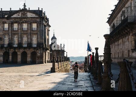 Une femme non identifiée marche seule par la place Obradoiro vide dans Santiago pendant la pandémie du coronavirus Banque D'Images