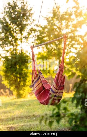 hamac vide dans le jardin à côté de l'arbre dans les lumières de coucher de soleil, concept de repos extérieur Banque D'Images