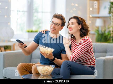 Bonne famille regardant le projecteur, la télévision, des films avec pop-corn le soir à la maison. Couple passant du temps ensemble. Banque D'Images