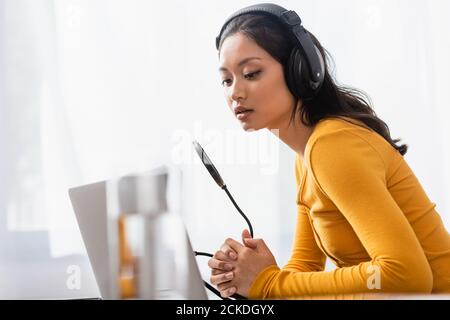 objectif sélectif de la chaîne de télévision asiatique dans le domaine des casques sans fil avec les mains serrées près du microphone Banque D'Images