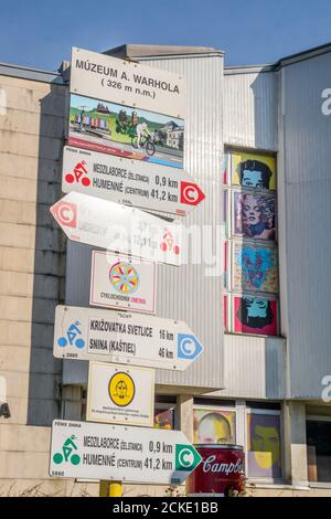 Panneau touristique avec l'inscription « Muzeum A. Warhola ». Bâtiment du musée en arrière-plan. Medzilaborce, Slovaquie orientale, Europe. Banque D'Images