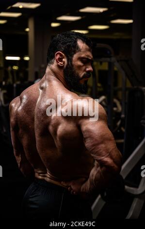 style de vie sain d'un beau jeune homme fort avec la barbe montrant muscle de son puissant sueur en arrière sombre sport gym Banque D'Images
