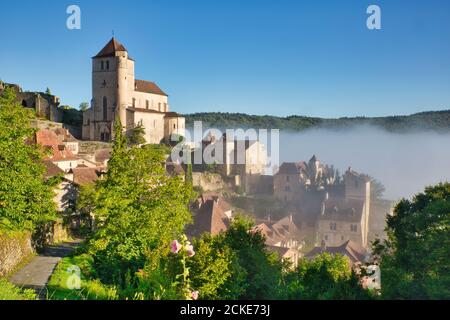 Brume matinale se délaçant du pittoresque village français de St Cirq-Lapopie avec son église, dans le midi-Pyrénées, Lot, Cahors, France Banque D'Images