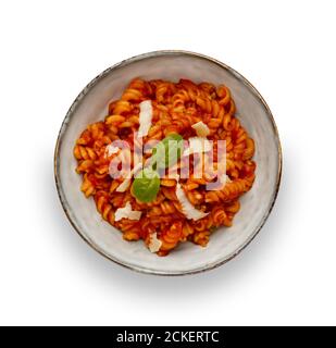 Un bol de délicieux pâtes de tomates dans un bol rustique, garni d'une branche de basilic, isolé sur du blanc avec une ombre portée Banque D'Images