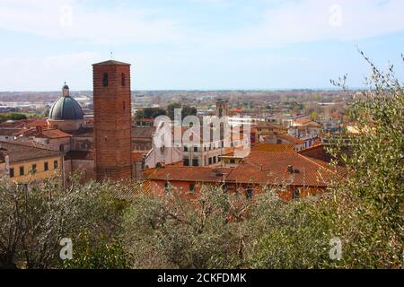 les toits rouges des maisons habitées, l'église et le clocher de la cathédrale pietrasanta vu du vert d'une colline au sommet Banque D'Images