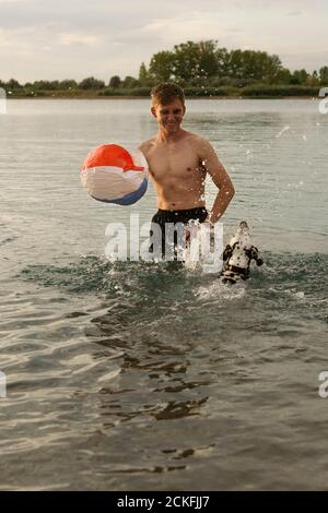 Un jeune homme joue avec un chien dalmatien dans le eau Banque D'Images