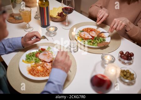 Gros plan d'un couple senior assis à la table et en train de manger délicieux plat pendant le dîner Banque D'Images