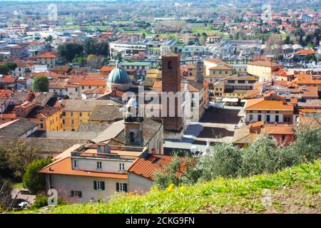 les toits rouges des maisons habitées, l'église et le clocher de la cathédrale pietrasanta vu du vert d'une colline au sommet Banque D'Images