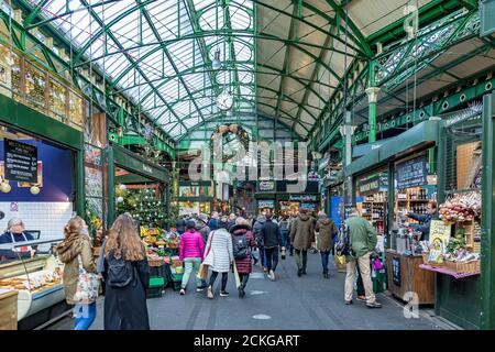 Les gens magasinent et naviguent dans les étals du marché sous le toit en verre et en fer forgé à Borough Market, Southwark, Londres Banque D'Images